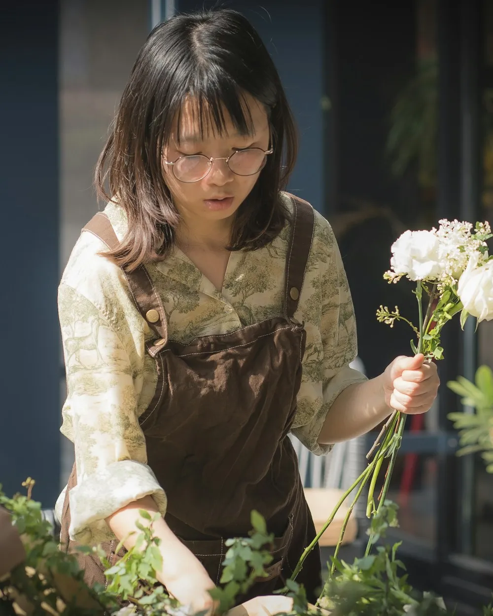 Florist med förkläde binder vita blommor